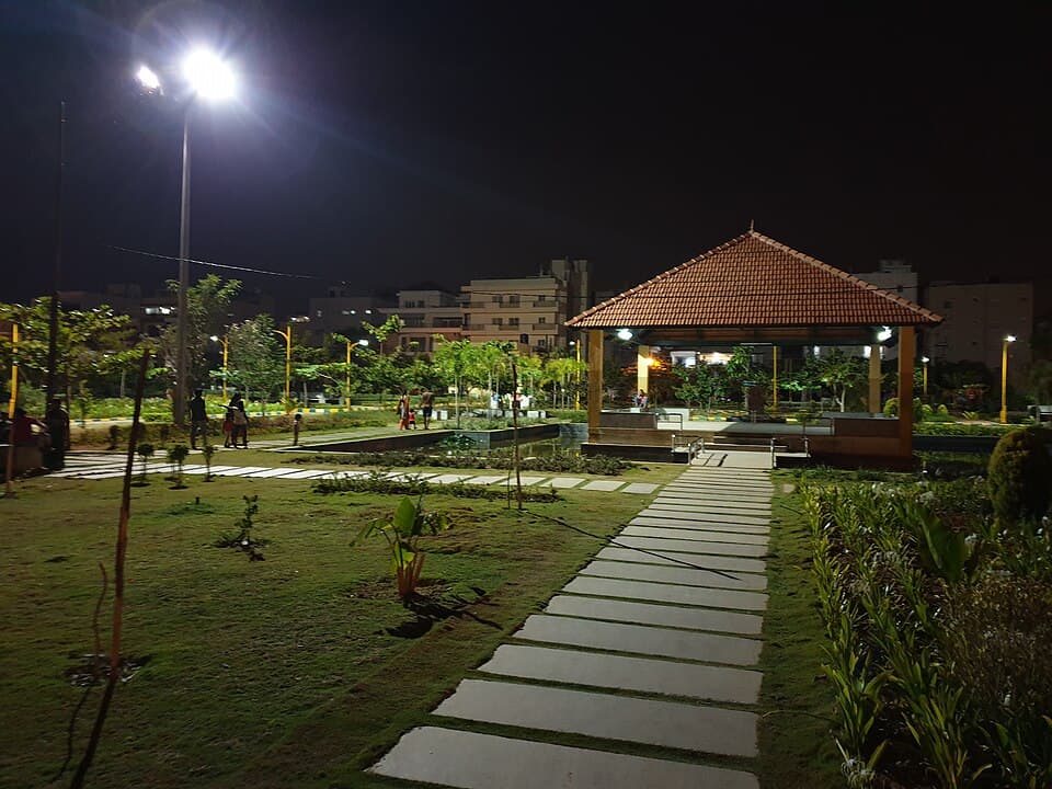 A lit neighbourhood park with a tiled pavilion in HSR Layout, Bengaluru, at night